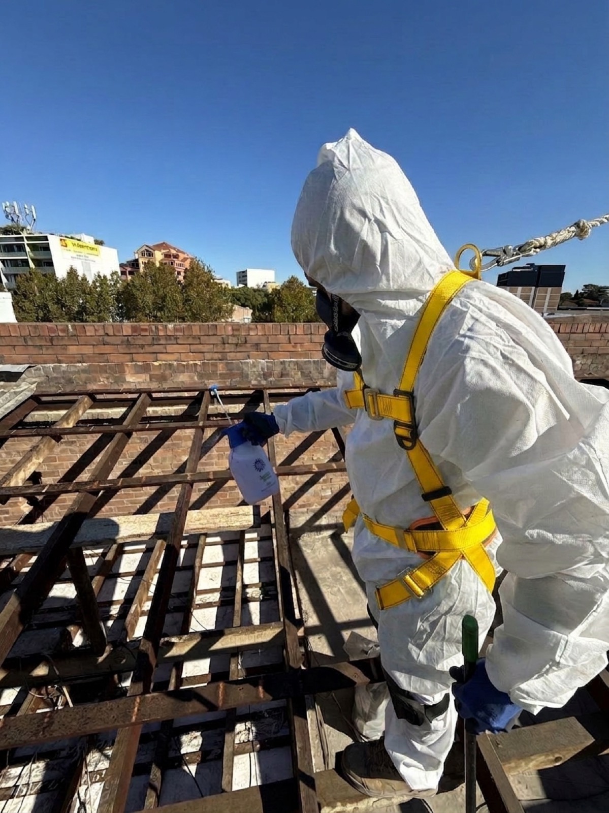 Operator in protective equipment stripping the asbestos roof, Rockdale